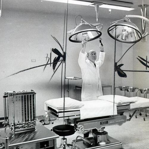 [Dr. Robert L. Edwards adjusting a surgical lamp in an operating room at French Hospital]