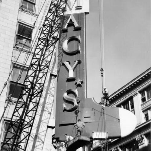 [Work crew converting Macy's sign into a giant Christmas stocking]