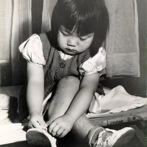 [Young girl tying her shoe]