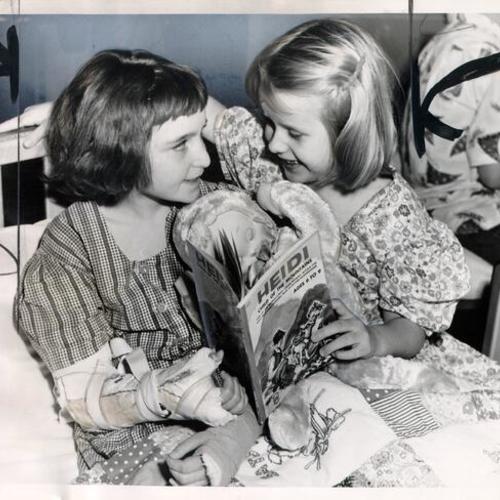 [Two patients reading a book together at Shriners' Hospital for Crippled Children]