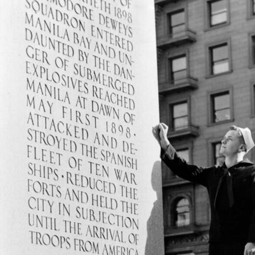 [Cletus M. Heicks reads the inscription on the Dewey Monument in Union Square]