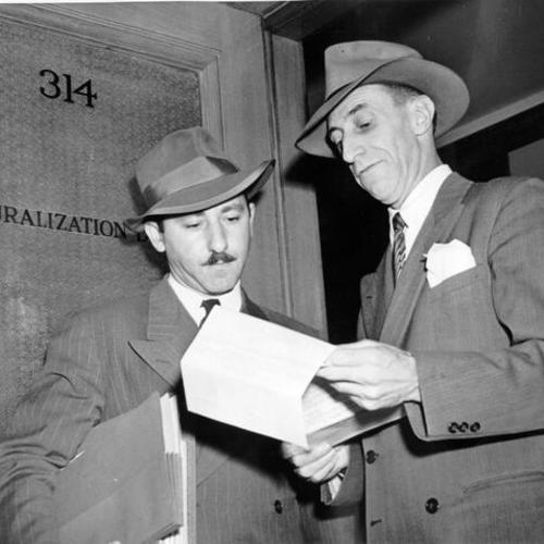 [Harry Bridges (right) confers with his attorney before entering the Naturalization hearing room in the San Francisco City Hall]