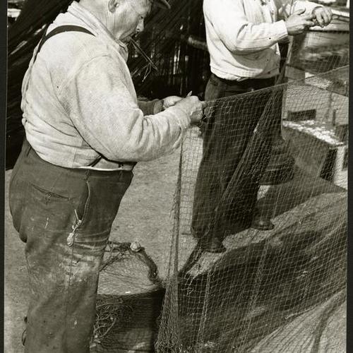 [Fishermen Pete and Joe Busalacchi working on a net at Fisherman's Wharf]