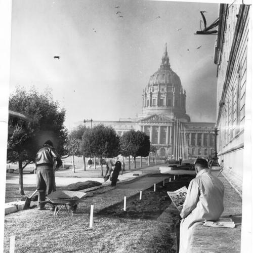 [View of City Hall from side of Main Library in 1960's while workers laying lawn in the foreground]