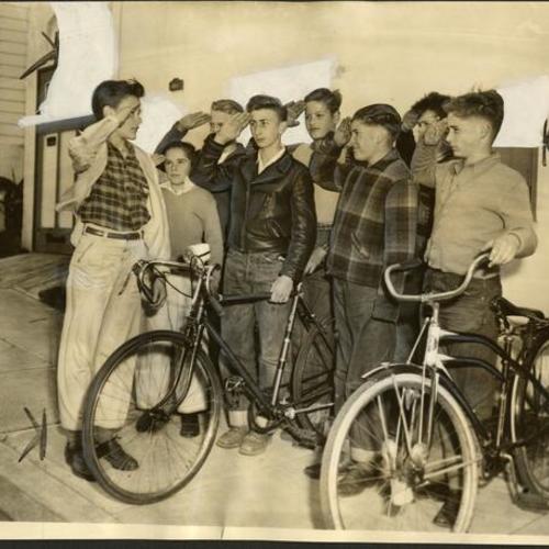 [Members of the Junior Victory Army bicycle corps saluting their group leader]