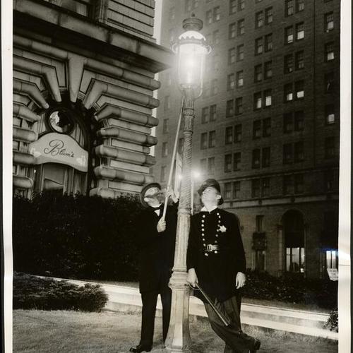 [William A. Baker and A. J. McCollum turning on a gas street light on the lawn of the Fairmont Hotel]