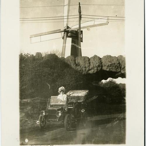 [Woman seated in automobile in front of windmill in Golden Gate Park]