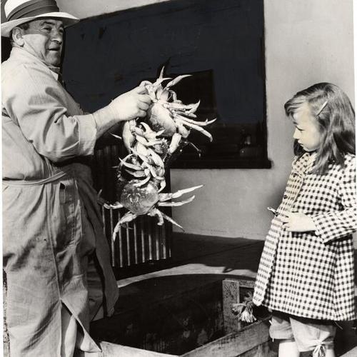 [Sal Strazzulo holding up a handful of crabs for tourist Janis Johnson]