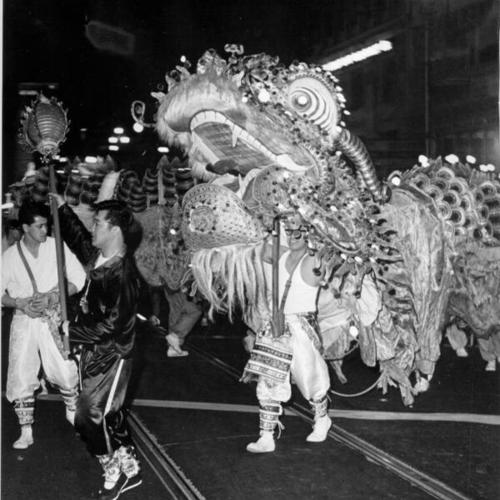 [125-foot dragon, propelled by 60 pairs of human legs, marching up Market Street in the Chinese New Year's Parade]