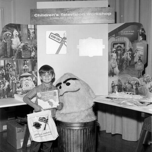 [Child posing with Sesame Street display during a Reading Fair at Commodore Sloat Elementary School]