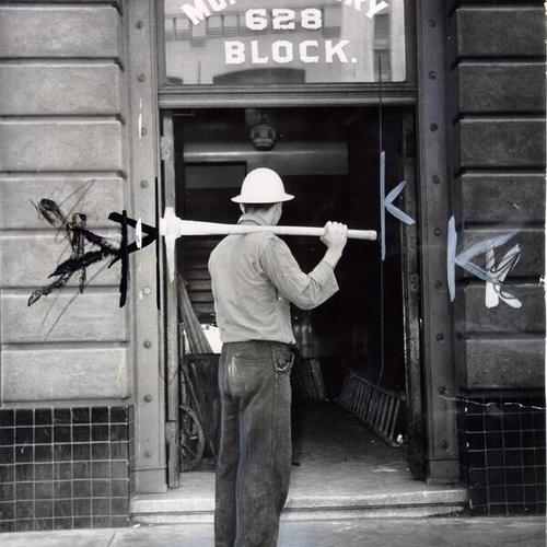 [Worker for a wrecking company standing at the entrance to the Montgomery Block building]