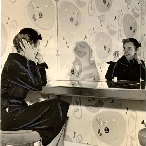 [Unidentified woman sitting in front of a mirror in a restroom at Ransohoff's]