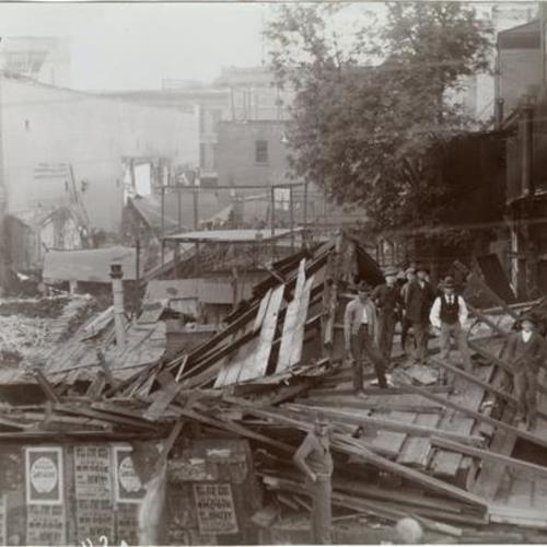 042 People standing on top of wooden building debris during demolition