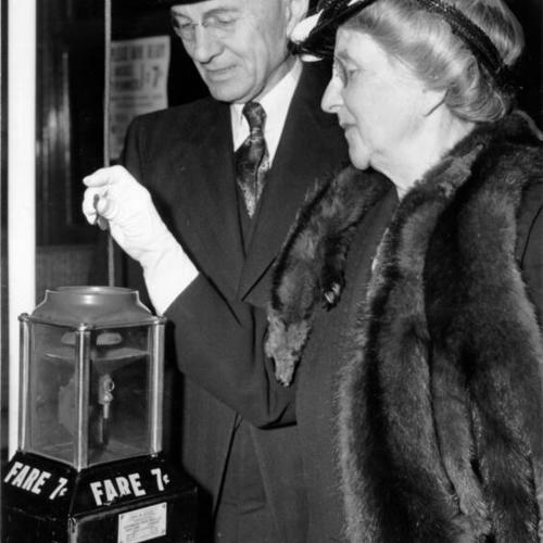 [Edward G. Cahill watching Mrs. Edward G. Cahill drop money into a fare box on a Municipal Railway streetcar]
