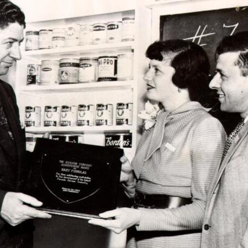 [Ruth and Edward Wenner receiving a plaque from L. S. Merrill of the Borden Company for the development of baby formula]