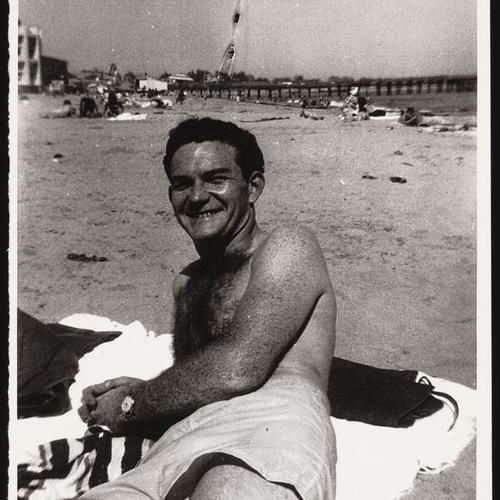 Bill Giddings in swim trunks lounging at beach