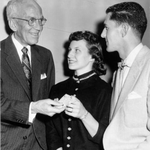 [L. G. Fox presenting Mr. and Mrs. Don Howard with a prize for being the 500,00th patrons to see "Cinerama Holiday"]