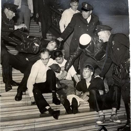 [Helmeted police restraining youths on City Hall steps after firehoses are turned on mob]