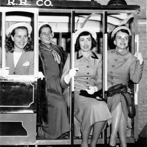 [Mrs. Frank Hinman, Miss Shirley Brown, Mrs. James Hart and Mrs. J. Max Moore posing on a model cable car]