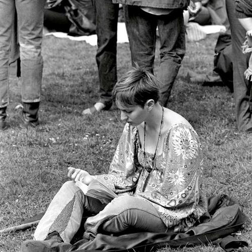 [Woman sitting on grass reading The Hobbit at a summer festival]