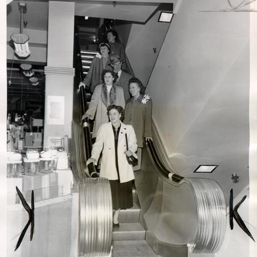 [People riding an escalator in the Weinstein Company department at 1041 Market Street]