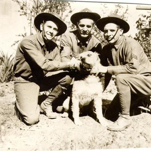 [Three soldiers posing with a dog during Army Day in San Francisco]