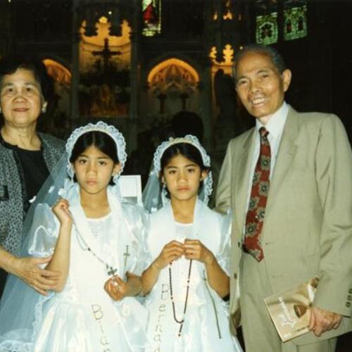 [Bernadette with her twin sister Bianca during their first communion at St. Paul's Church along with grandparents]