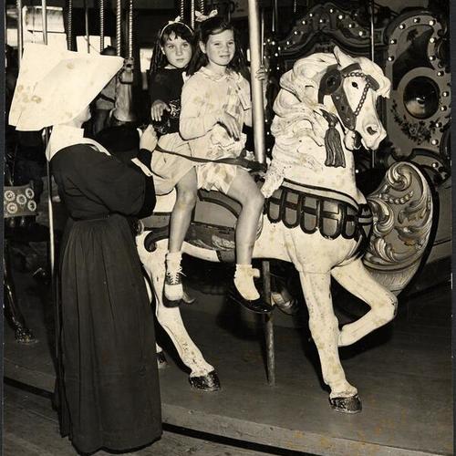 [Sister Gertrude helping two girls from St. Joseph's Orphanage onto the Merry-Go-Round at Playland at the Beach]