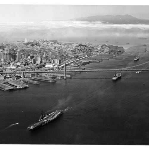[Aircraft carriers  U.S.S. Midway, Kearsarge and Hancock pass under Bay Bridge with other ships of the First Fleet trailing behind]