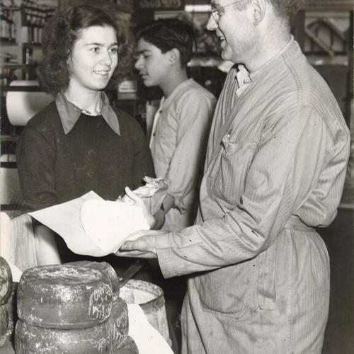 [Andrew Peters, proprietor of the Olympia Grocery store, with customer Charlotte Lassalette]