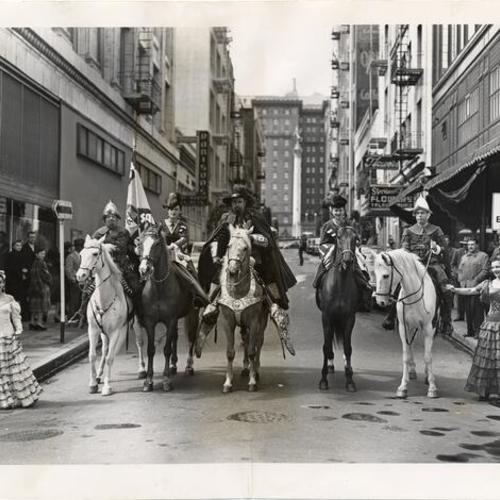 [Don Gaspar De Portola flanked by two women and two body guards posing on horses on Maiden Lane]