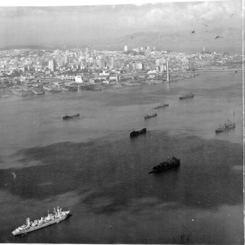 [Fleet of cargo ships at anchor beside Bay Bridge]