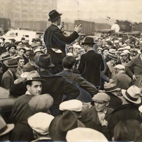 [John Schumacker addressing a crowd of longshoremen and teamster pickets at the waterfront]