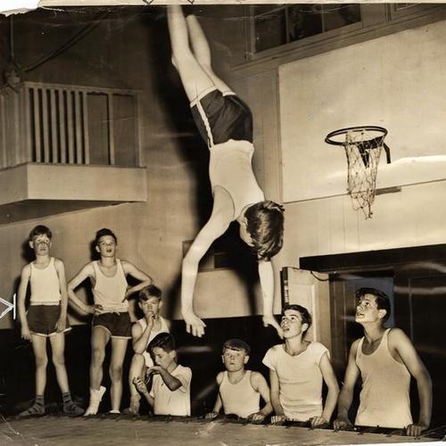 [Harry Chambers demonstrating a back flip on trampoline to other members of the San Francisco Boys' Club]