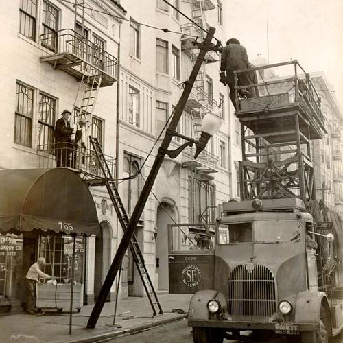 [Workers from the Department of Electricity repairing a fallen light pole on O'Farrell Street]