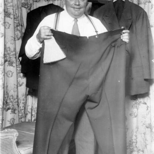 [Roscoe "Fatty" Arbuckle holding up pair of pants]