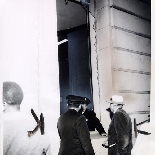 [Police officers examining one of two windows broken by an earthquake at the Market and Jones branch of the Anglo-California Bank]