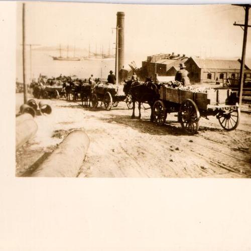 [Line of horse-drawn wagons heading towards the San Francisco waterfront]