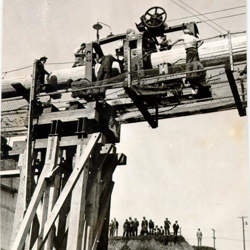 [Workers using a cable squeezer during construction of the San Francisco-Oakland Bay Bridge]