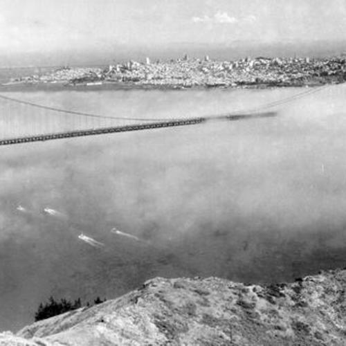 [Aerial view of fog over Golden Gate Bridge toward San Francisco]
