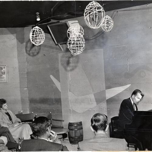 [William Corbett Jones performs on piano for an audience at the Opus One nightclub]