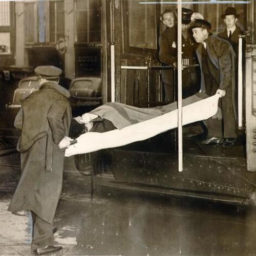 [Lora Weinman being carried off of a Municipal streetcar on a stretcher after she slipped and fractured her leg]