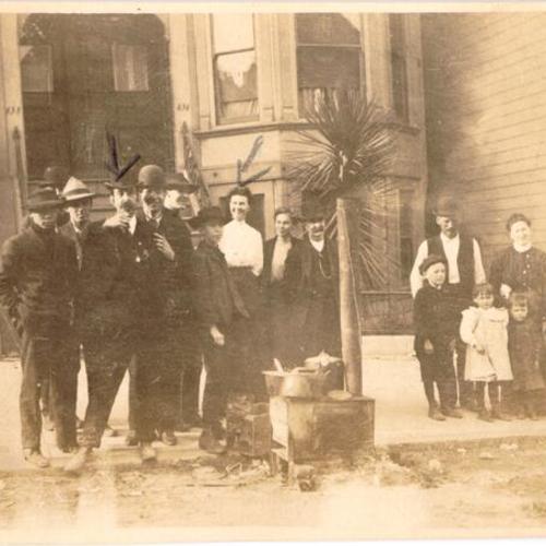 [Group of people posing by a small street kitchen on an unidentified street]