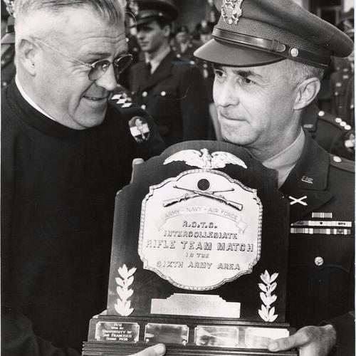 [Father William J. Dunne of the University of San Francisco accepting a trophy won by school's the rifle team]