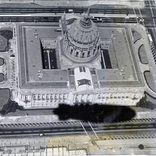 [Aerial view of the Civic Center Plaza with shadow of blimp over Polk street entrance of City Hall]