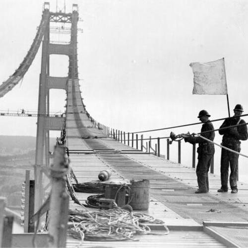 [Workmen laying cables on Golden Gate Bridge catwalk]
