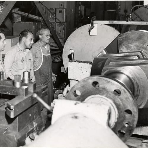[Machinists working on a Diesel engine at San Francisco Naval Shipyard at Hunter's Point]