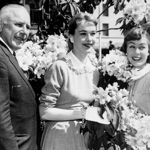 [Roy N. Buell, president of the Down Town Association, Lona Crawford and Kari Sandino, models, inspect the rhododendrons blossoming in Union Square]