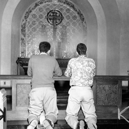 [Students Jim Clifford and Jack Butler kneeling during meditation in the Riordan chapel]