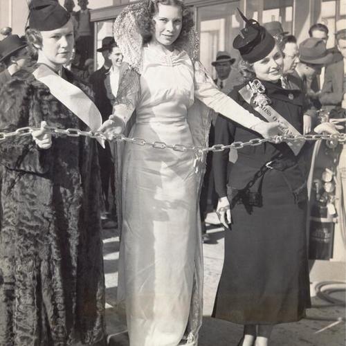 [Eleanor Wise, titled Miss Berkeley, Ardis Cummins, titled International Queen, and Ola Entrikin, titled Miss Oakland holding the chain barrier of the bridge at opening ceremony for San Francisco-Oakland Bay Bridge]